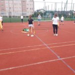 Dziewczyna i chłopak grają w mini tenisa, a obok koleżanka przygląda się ich wyczynom