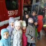 uśmiechnięte dzieci oglądają stroje strażaków