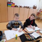 Chłopcy siedzą w klasie i pracują przebrani za Batmana i Harrego Pottera