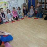 Siedząc w kole dzieci uczą się jak prawidłowo wykonać masaż serca