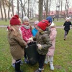W parku dzieci wkładają odpady do worka.
