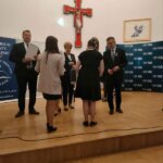 Dwie uczennice stojące tyłem odbierają nagrodę od Ministra Edukacji i Nauki