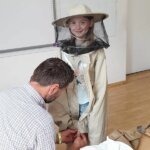 Dziewczynka prezentuje strój pszczelarza