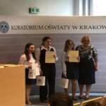 Trzy uczennice trzymają dyplomy i nagrody, obok nich stoi Pani Kurator Małopolski