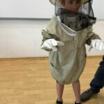 chłopczyk stoi ubrany w strój pszczelarza