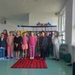 Dzieci stoją w dwóch rzędach i śpiewają piosenki