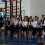 Uczniowie stoją w trzech rzędach i śpiewają piosenkę