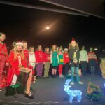 Dzieci w strojach świątecznych stoją na scenie