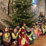Mikołajkowa wycieczka do Bochni. Dzieci z wychowawczynią przy świątecznie ubranej choince w kaplicy w kopalni soli