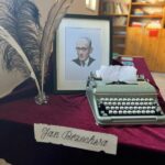 Na stole stoi portret Jana Brzechwy, maszyna do pisania, trzy duże pióra w kałamarzu