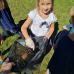 Dziewczynka w rękawiczkach jednorazowych trzyma worek na śmieci