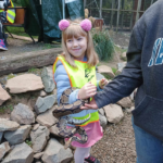 Dziewczynka trzyma na ręku węża i się uśmiecha