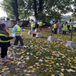 Dzieci chodzą ze zniczami po cmentarzu i kładą je na groby żołnierzy