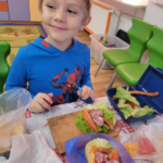 chłopiec pokazuje swoje kolorowe kanapki na talerzyku
