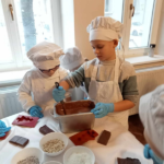 Dwóch chłopców w strojach cukierników miesza ciepłą czekoladę