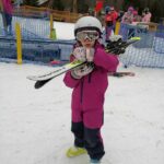 Dziewczynka niesie narty