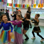 Dziewczynki w kolorowych strojach tańczą na balu