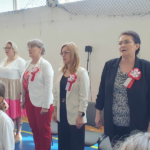 Panie Dyrektor, nauczycielka oraz dzieci śpiewają na baczność hymn Polski