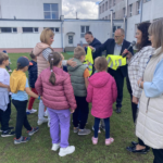 Klasa 1b odbiera kamizelki odblaskowe od przedstawiciela gminy. Obok stoją panie dyrektor