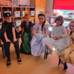 dzieci w strojach karnawałowych siedzą na krzesłach i pozują do zdjęcia