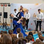 Pani i pan tańczą walca, za nimi panowie grają na instrumentach