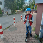 Chłopiec pozuje do zdjęcia w kasku i z hulajnogą
