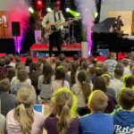 mężczyzna stoi na scenie i gra na gitarze