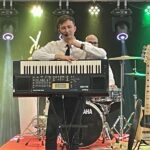 mężczyzna stoi na scenie i prezentuje instrument