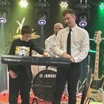 mężczyzna i chłopiec stoją za instrumentem, chłopiec gra