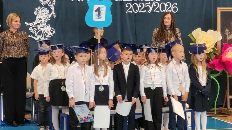 Grupa dzieci z klasy 1c stoi i śpiewa piosenkę