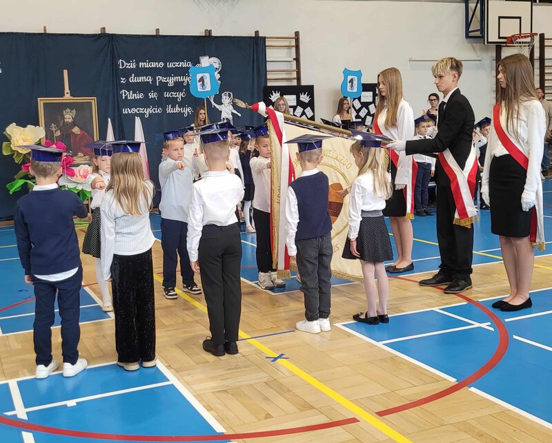 Sześciu uczniów z klas pierszych stoi i składa ślubowanie przy sztandarze szkoły