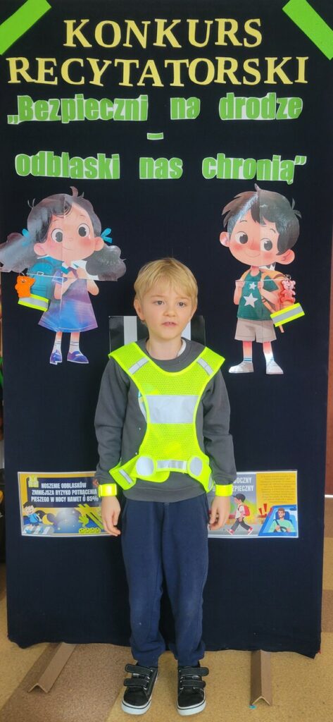 Chłopiec ubrany w kamizelkę odblaskową recytuje wiersz