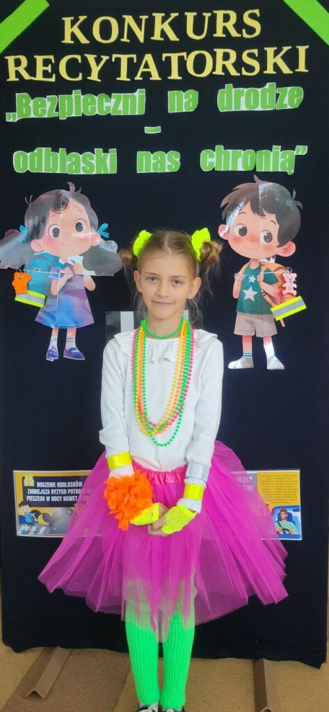 Dziewczynka w odblaskowym stroju i z kolorowymi koralami recytuje wiersz