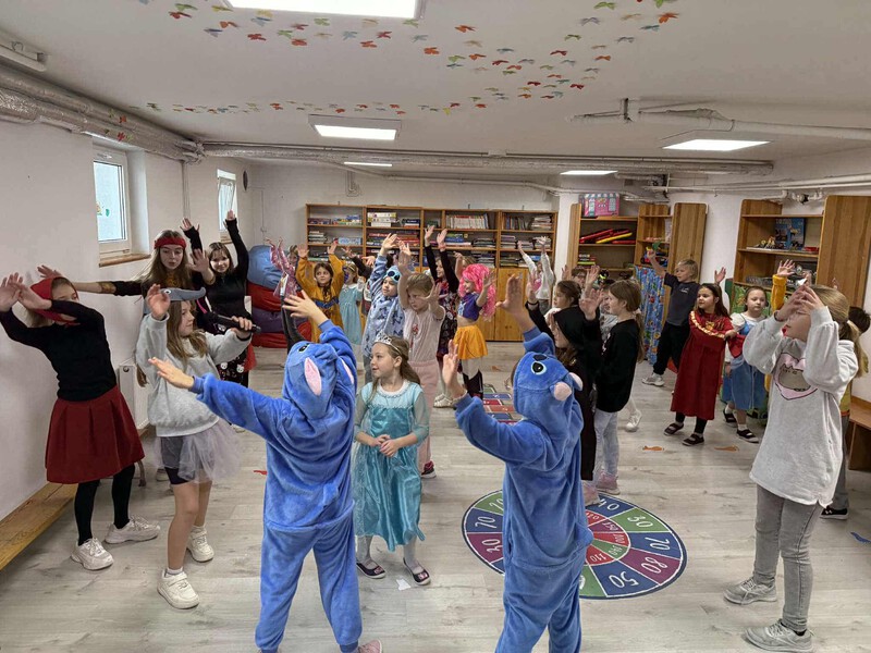 Duża grupa dzieci tańczy w strojach postaci z bajek
