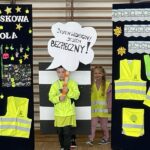 Uczeń wchodzi na pokaz mody, trzyma tablicę z hasłem.