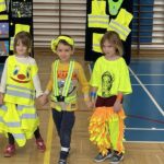 Dwie dziewczynki i chłopiec prezentują swoje stroje odblaskowe.