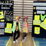 Chłopiec z dziewczynką prezentują swoje stroje odblaskowe.