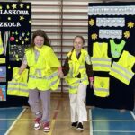 Dwie dziewczynki prezentują stroje odblaskowe.