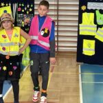 Chłopiec i dziewczynka prezentują stroje odblaskowe.