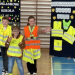 Dwóch chłopców i dziewczynka prezentują modę odblaskową.