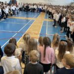 Cała społeczność szkolna stoi i śpiewa hymn.