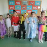 Siedmioro dzieci stoi obok siebie w strojach postaci z bajek