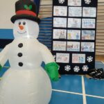 Dekoracja- dmuchany bałwan i tablica z informacjami jak bezpiecznie spędzić ferie.