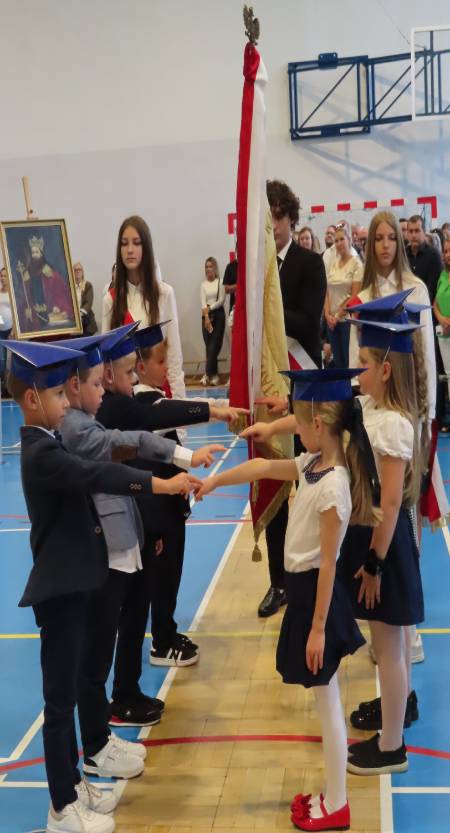 Uczniowie ślubują z wyciągniętymi rękami w stronę sztandaru szkoły