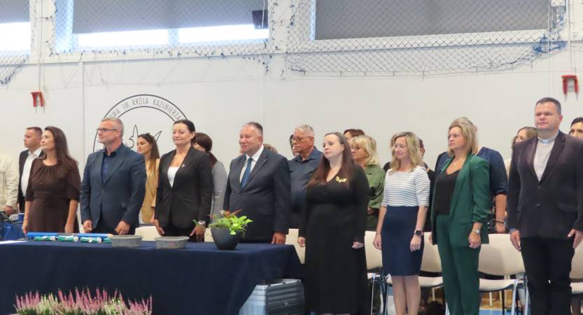 Na zdjęciu widać dyrektora szkoły i zaproszonych gości w czasie hymnu